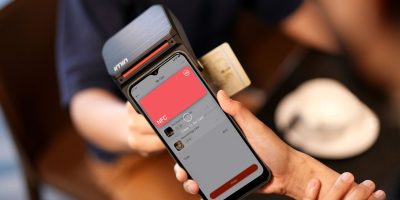 Close de um smartphone sendo aproximado de um terminal para realizar um pagamento digital sem contato