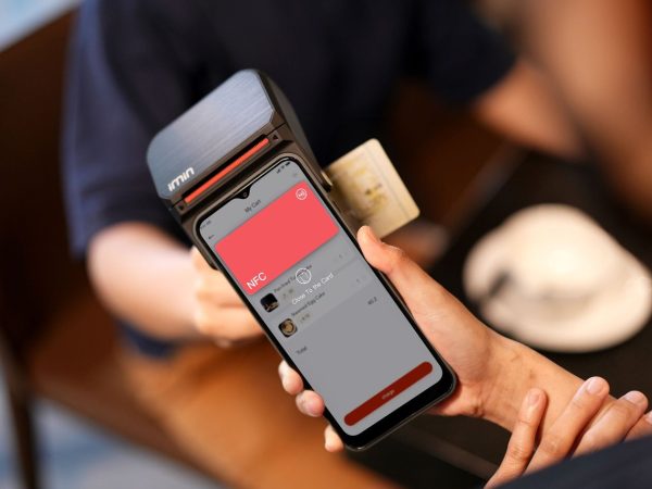 Close de um smartphone sendo aproximado de um terminal para realizar um pagamento digital sem contato