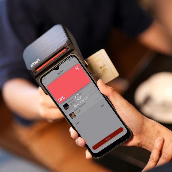 Close de um smartphone sendo aproximado de um terminal para realizar um pagamento digital sem contato