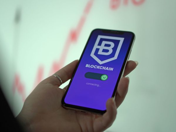 Mão segurando um smartphone que exibe uma carteira digital de criptomoedas.