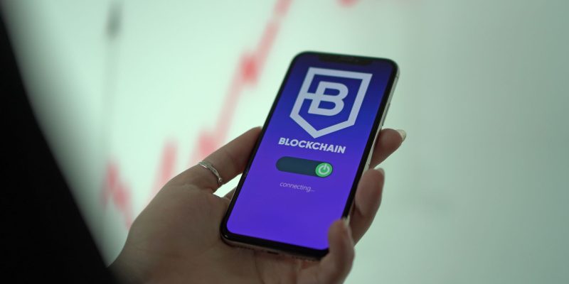 Mão segurando um smartphone que exibe uma carteira digital de criptomoedas.