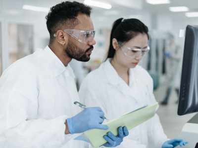 Dois cientistas realizam pesquisas em conjunto em um laboratório moderno, cercados por equipamentos científicos.
