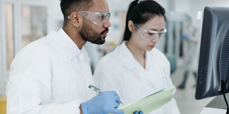 Dois cientistas realizam pesquisas em conjunto em um laboratório moderno, cercados por equipamentos científicos.
